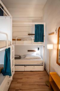 1 dormitorio con 2 literas y cortinas azules en Soul Backpackers Barcelona, en Barcelona 90 fotos más