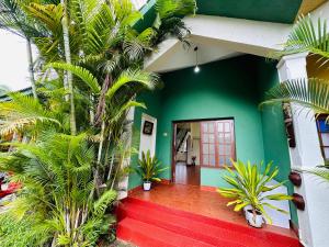 a green house with palm trees and a red porch at Sana Villa & Resort Goa in Anjuna +52 photos