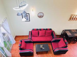 a living room with a red couch and a table at Sana Villa & Resort Goa in Anjuna