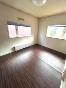 an empty room with two windows and a wooden floor at Nature Moiwa in Sapporo