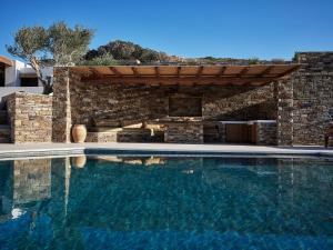 uma piscina em frente a uma casa com uma parede de pedra em Liostasi Ona Villa em Ios Chora