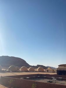 a row of tents in the desert with mountains in the background at عماد رم in Wadi Rum