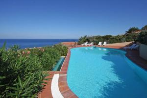 a swimming pool with chairs and the ocean in the background at Rosmarino veranda and pool with sunset view in Costa Paradiso