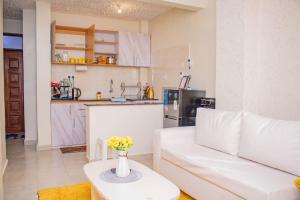 a living room with a white couch and a kitchen at Yellow Petals Homestays in Nanyuki