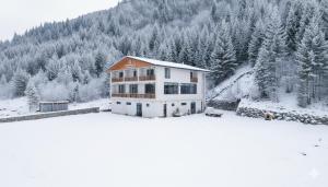 a house in the snow with trees in the background at Hotel - Jodi Lare in Zardlashi