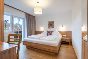 ein Schlafzimmer mit Bett, Schreibtisch und Fenster in der Unterkunft Alpenhof Wängle in Reutte