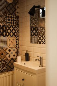 um banheiro com uma pia e alguns azulejos em Bb's Cosy Apartments em Braşov