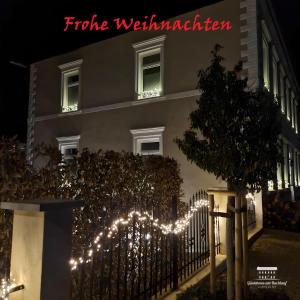 un edificio con luci di Natale davanti a una recinzione di Komfort Ferienwohnungen mit Wellness-Garten - Gästehaus am Bachlauf - Losheim am See a Losheim