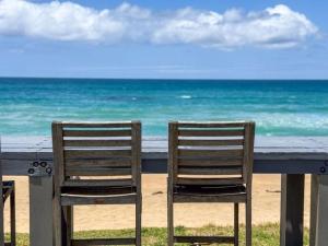 科夫斯港Nautilus Beach Resort by Charlesworth的海滩上，栏杆上放着两把椅子。