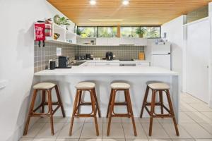 科夫斯港Nautilus Beach Resort by Charlesworth的厨房配有白色柜台和3个酒吧凳