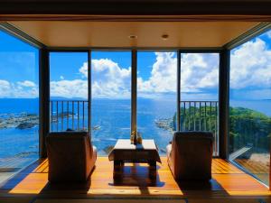 a living room with two chairs and a large window at Ocean View Hiromi SPA Hotel温泉と絶景の宿 in Shimoda