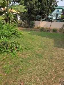 une cour herbeuse avec une maison en arrière-plan dans l'établissement Indrapuri Home Stay, à Bolpur