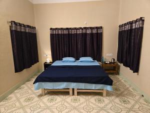 - une chambre avec un lit bleu et des rideaux noirs dans l'établissement Indrapuri Home Stay, à Bolpur