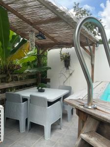 a table and chairs under a wooden pergola at Résidence Flores De Maria in Le Marin