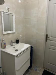 Un baño con un lavabo blanco y un espejo. en Vasso, en Nancy