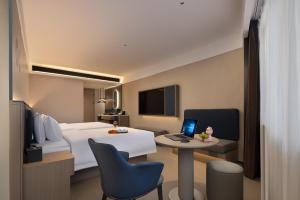 a hotel room with a bed and a desk with a laptop at Xi Gu Hotel Wuhan Xudong Metro Station Branch in Wuhan +8 photos