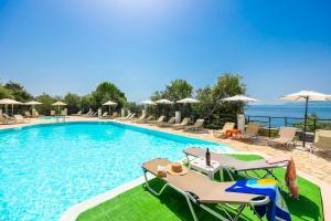 a large swimming pool with chairs and umbrellas at Nissaki Sea View Hotel in Corfu