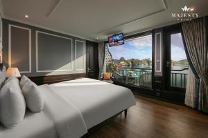 a bedroom with a bed and a balcony with a television at Majesty Luxury Prime Cruise by Premier Group in Ha Long