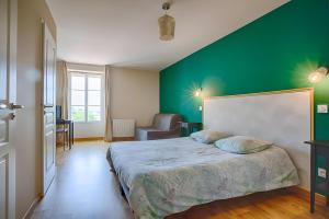 a bedroom with a green wall and a bed at La Maison D'hana in Saint-Bonnet-de-Valclérieux