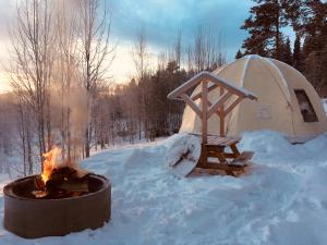 un braciere nella neve accanto a una tenda di Romantic night in a dome tent lake view a Bjuråker Altre 18 foto
