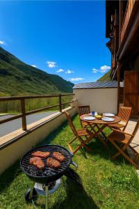 un barbecue avec de la viande dessus à côté d'une table dans l'établissement Vall Fosca - Apartamento con espectaculares vistas y jardín privado, à Torre de Capdella
