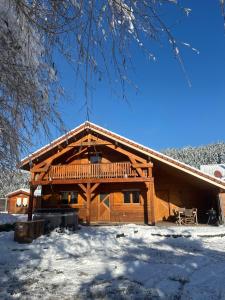 a log cabin with snow on the ground at Le Chalet de la Devinière, bain nordique extérieur chauffé in Xonrupt-Longemer