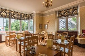 ウィンダミアにあるWindermere Park B&B inc Free off-site Health Clubのテーブルと椅子と窓のあるダイニングルーム