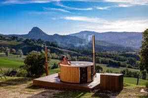 two people sitting in a hot tub in the mountains at Palazzo Serre - Natura & Piscina in San Leo