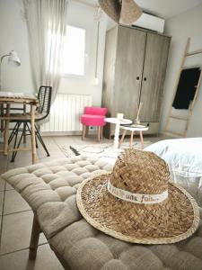 Un sombrero de paja sobre una otomana en un dormitorio. en La Petite Escale, en Lunel
