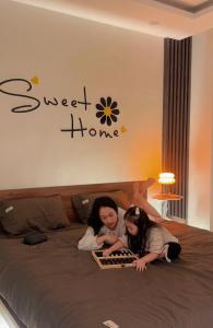 two girls laying on a bed with a book at Huế Nestory Homestay in Thôn Trường Giang