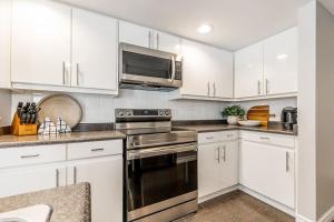 een keuken met witte kasten, een fornuis en een magnetron bij Alpine Hideaway - Walk to Blue Mountain in Blue Mountains