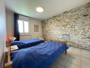 a room with two beds and a stone wall at Loustaou in Bidache