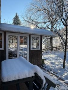 a snow covered bench in front of a house at Ferienwohnung Schmidt - Natur und Ruhe in Schwaigen