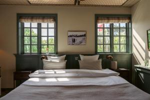 a bedroom with a large white bed with windows at Helenekilde Badehotel in Tisvildeleje