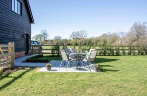 a patio with two chairs and a table in a yard at Barney's Barn in Woodbridge