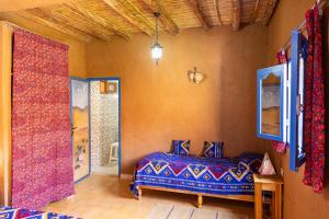 um quarto com uma cama com lençóis azuis e vermelhos em La Maison de l'Homme Bleu em Aït Boukha