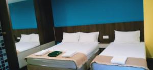 two twin beds in a room with a blue at Casa D'rose Hotel in Malacca