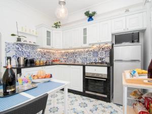 a kitchen with white cabinets and blue and white tiles at Casa Emar in Massa Lubrense