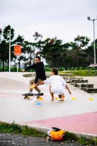 two men skateboarding on a sidewalk with a man on a skateboard at Arena Surf Hotel in Somo +11 photos