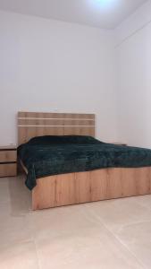 Cama en habitación blanca con marco de madera en Timbaki Theodosia T Brothers, en Tympáki