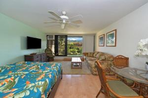 a bedroom with a bed and a couch and a ceiling fan at Kaleialoha 402 · KA 402 Spacious Studio Close to Ocean Heated Po in Kahana