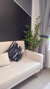 a white couch with a black pillow and a plant at Amber Cove - Luxury Design By Luxpro Management - 6~7 pax in Melaka