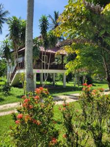 a house with a tree and flowers in front of it at Nazo Boutique Bungalows in Wok Tum