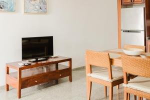een woonkamer met een tafel met een televisie en stoelen bij Playa Chica apartment in Puerto del Carmen
