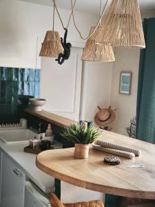 a kitchen with a wooden table and two hanging lights at La Petite Escale in Lunel