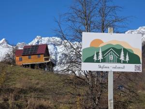 a sign in front of a house with snow covered mountains at SkyGona in Ghebi +1 photo