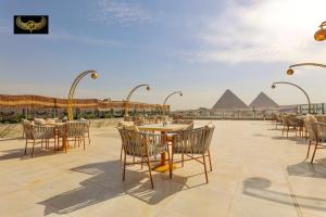 a patio with tables and chairs in front of the pyramids at Giza Inn Comfort view in Cairo