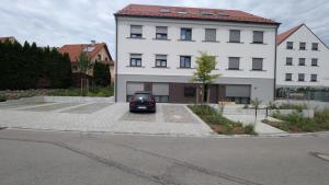 ScheyernDesign Apartment Bavaria - Küche, Smart-TV & Mehr的一辆停在白色建筑物前的汽车