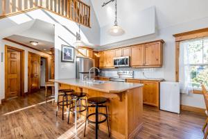 una cucina con armadi in legno e un'isola con sgabelli da bar di Still Winds - Private Patio - Shuttle to Blue a Collingwood