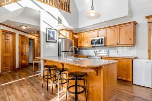 una cucina con armadi in legno e un'isola con sgabelli da bar di Still Winds - Private Patio - Shuttle to Blue a Collingwood Altre 36 foto